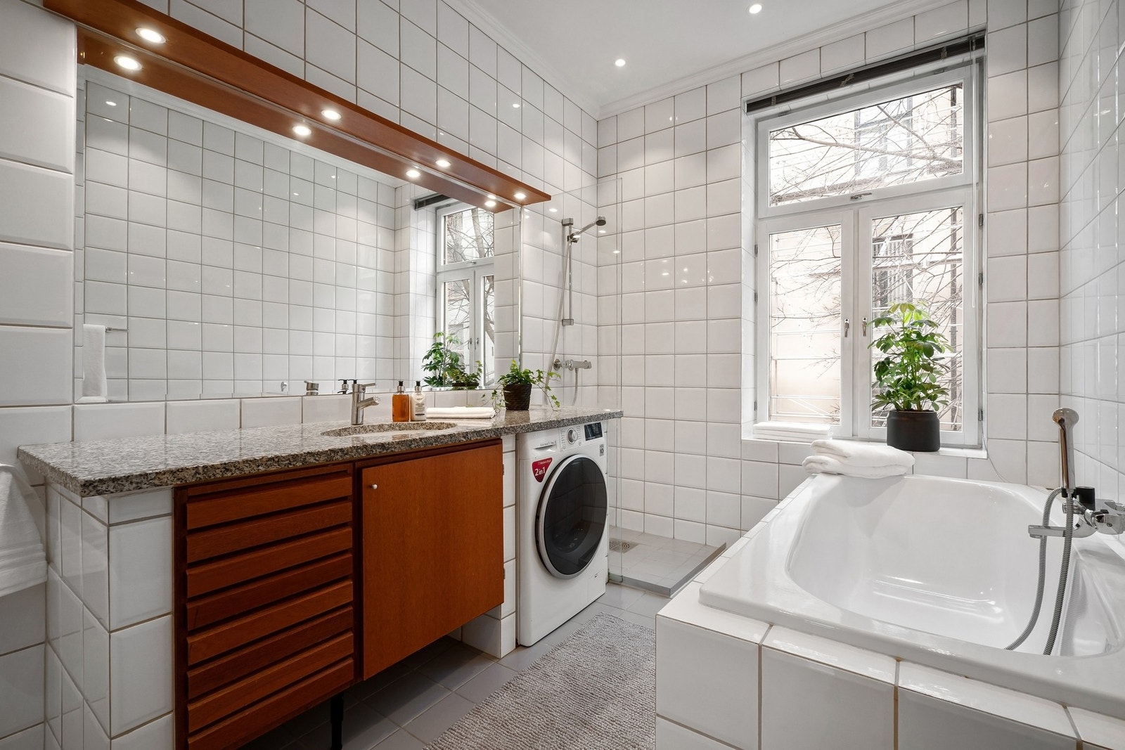 Romslig baderom med innfliset badekar, dusjnisje og gulvstående klosett. Galleribilde