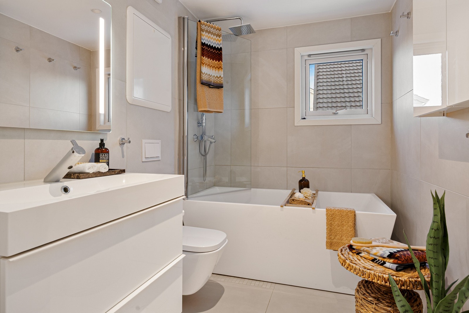 Strøkent bad med badekar, 60x60 fliser og mosaikk i dusjsonen. Perfekt for både avslapning og hverdagskomfort. Galleribilde