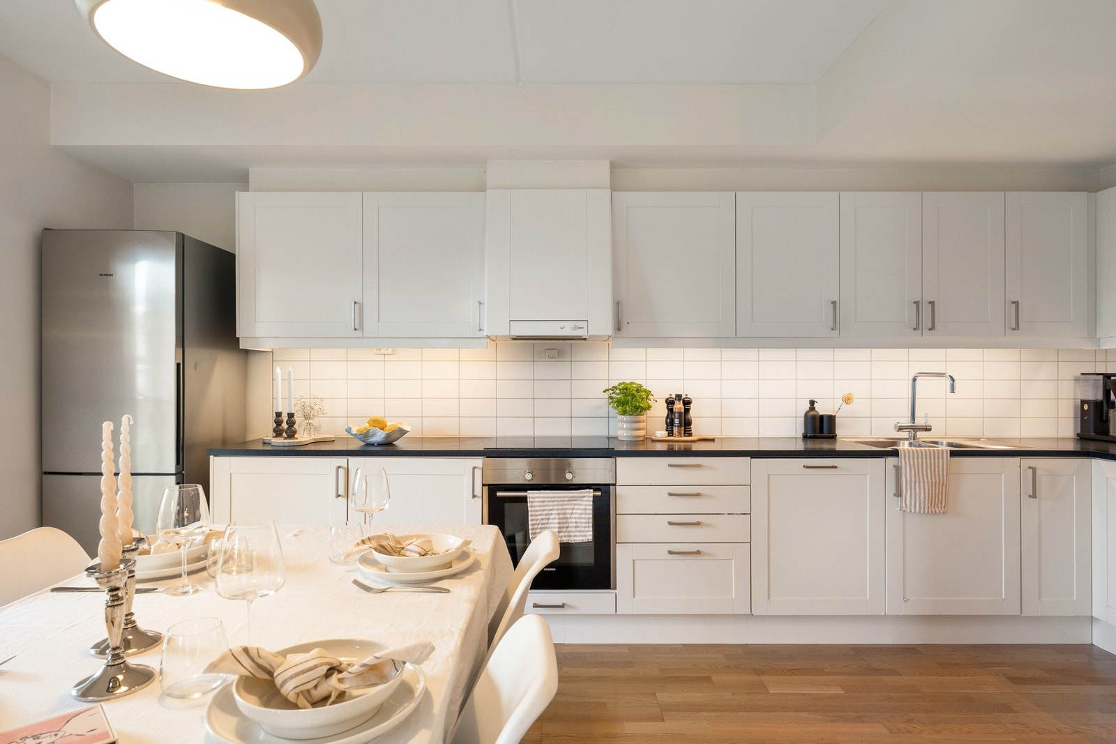 Innredningen har hvite, profilerte fronter kombinert med laminert benkeplate og fliser mellom benk og overskap. Galleribilde