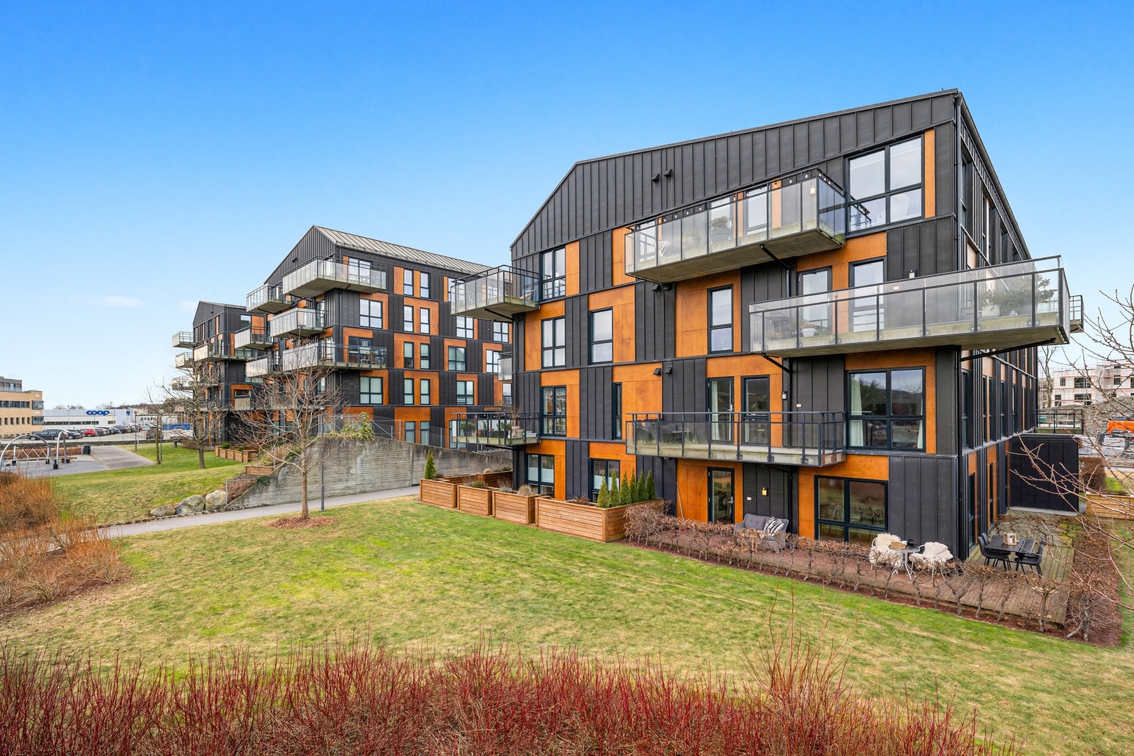 Utenfor terrassen ligger sameiets grønne fellesarealer med gressplener, busker og beplantning. Galleribilde