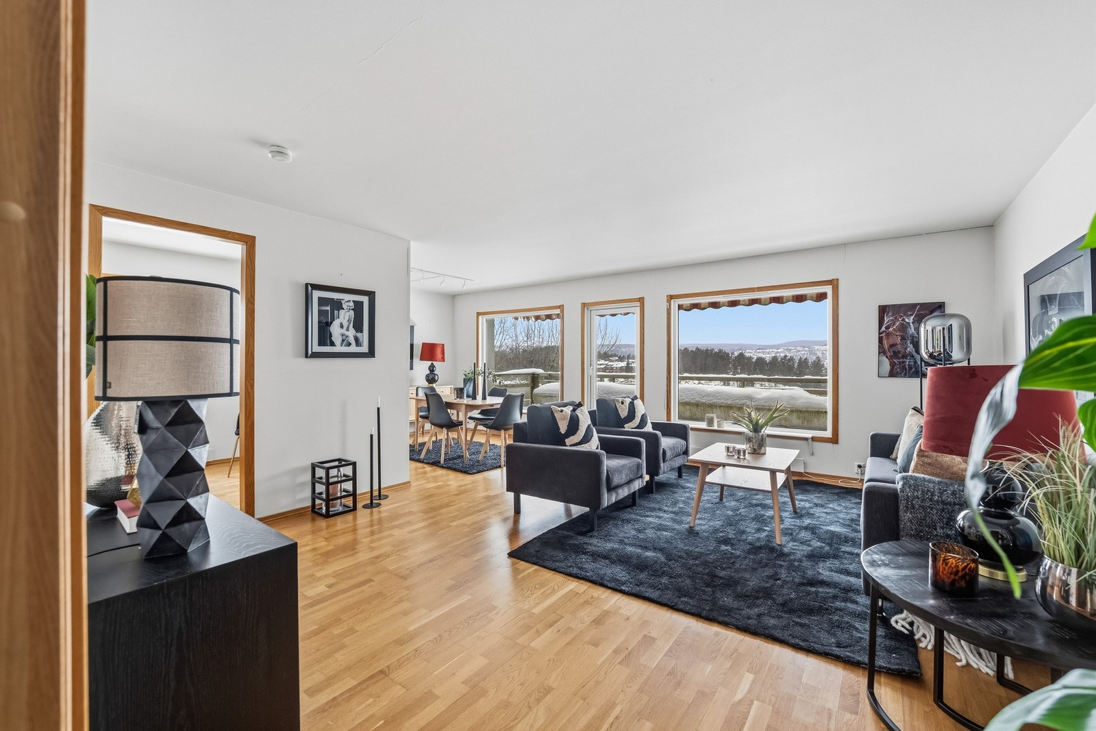 Stor og romslig stue med trestavsparkett på gulvet og lyse vegger. Galleribilde