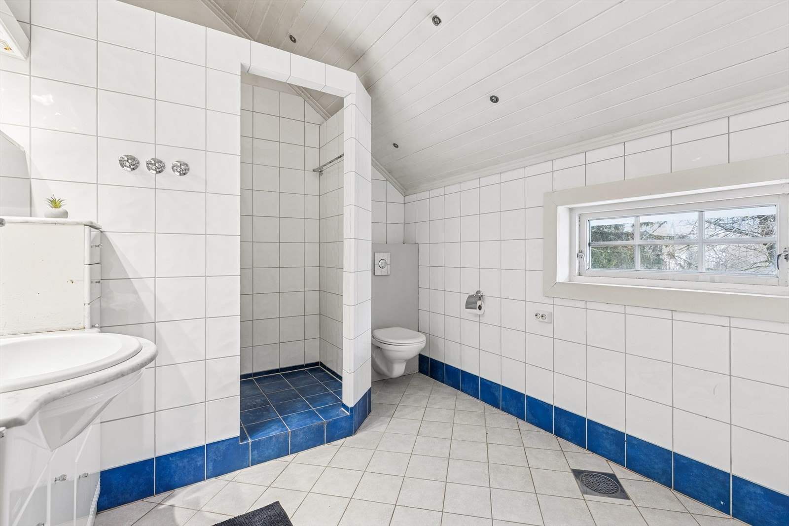 Innredningen har glatte fronter, og sanitærutstyret inkluderer en dusjnisje med dusj på gulvet, veggmontert klosett med innebygget sisterne og en praktisk servant. Galleribilde