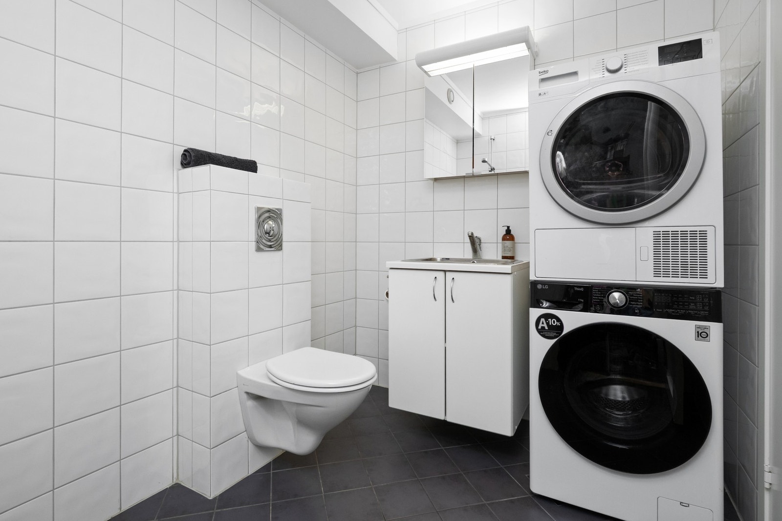 Bad/vaskerommet har praktisk innredning med skyllekum, dusj, veggmontert toalett og opplegg for vaskemaskin. Galleribilde