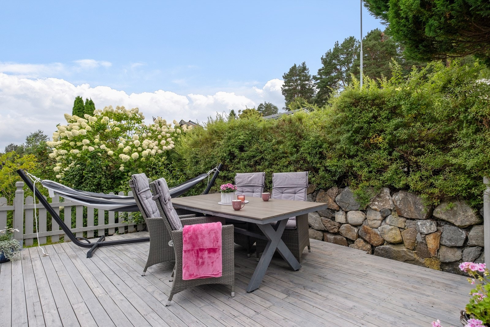 Terrasseområdet er omgitt av frodig vegetasjon og gir en skjermet uteplass. Galleribilde