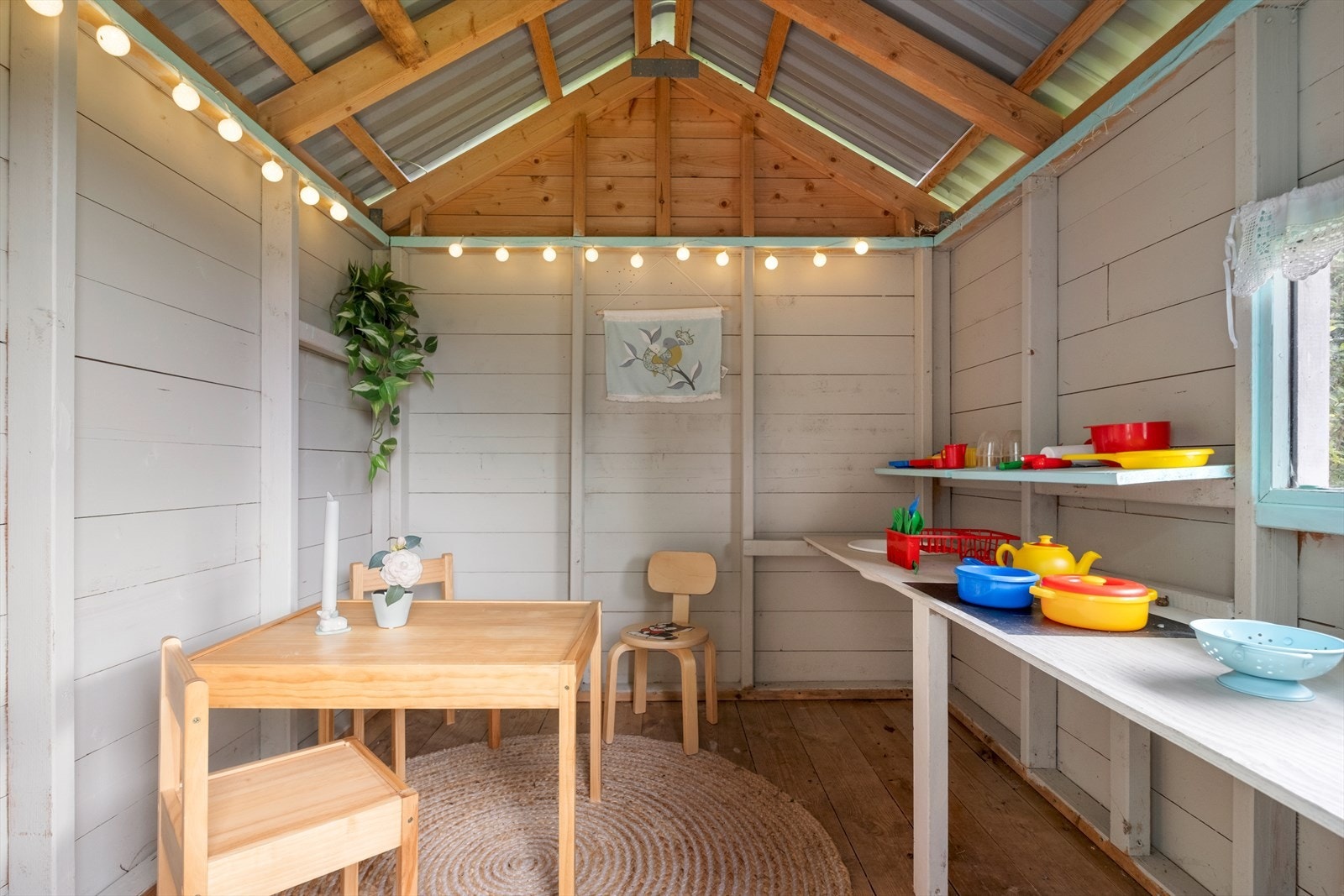 Interiøret i uteboden består av enkle tremøbler og hyller, med lyslenker som gir et koselig preg. Galleribilde