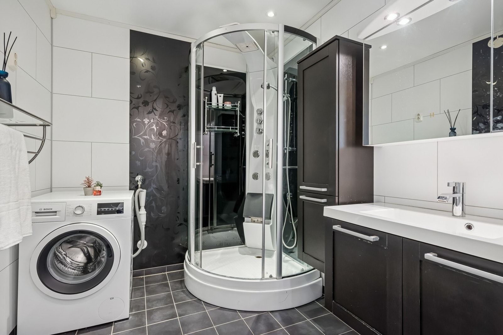 Badet ble oppgradert i 2012 og fremstår pent og moderne, med flislagt gulv med gulvvarme, baderomsplater på vegger og malte flater i himling. Her er vegghengt servantinnredning, speilskap med overlys, dusjkabinett og opplegg for vaskemaskin. Galleribilde