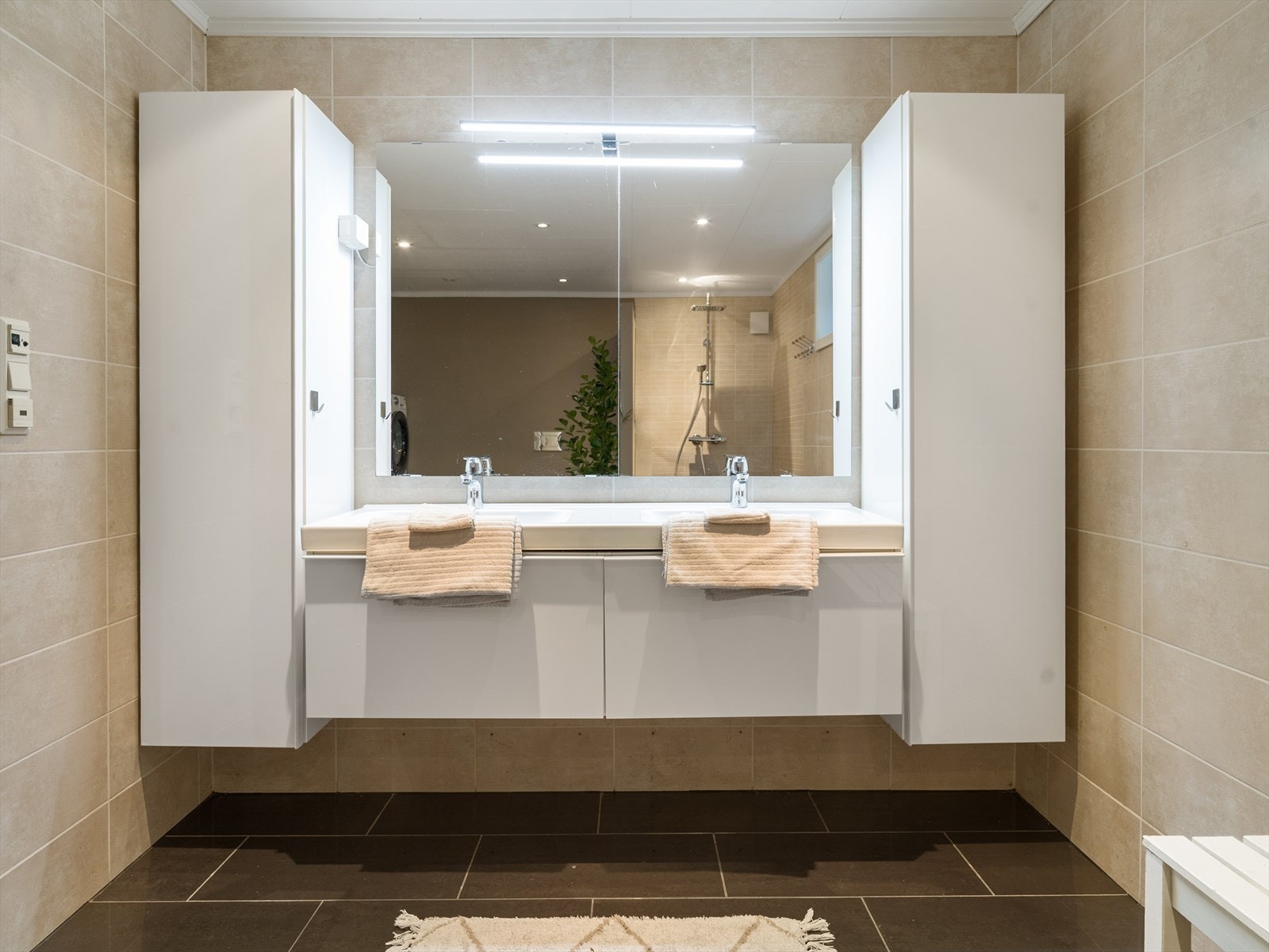 Veggene har overflater med fliser og microsement/våtromsmaling, mens himlingen har malte/folierte plater med downlights. Galleribilde