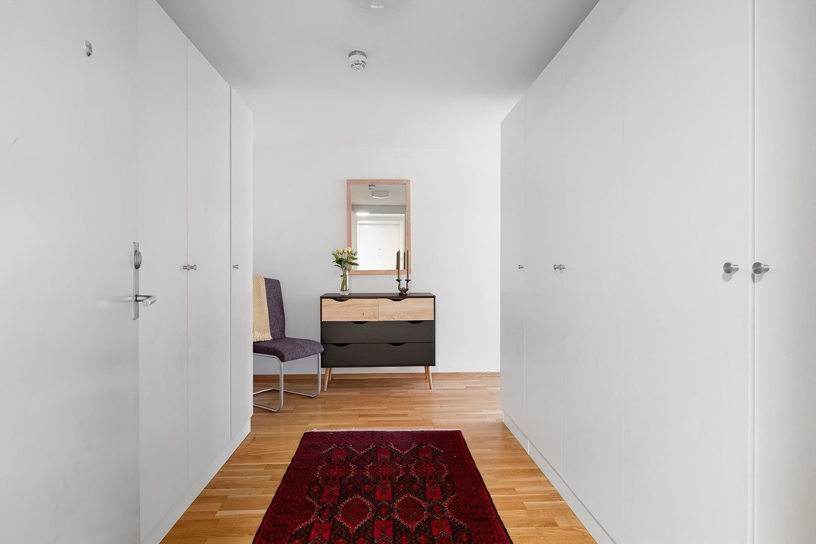 Romslig og hyggelig entré med garderobeskap på begge sider Galleribilde