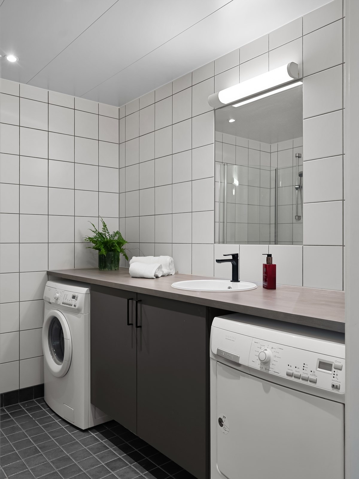 Badet er innredet med servant, servantskap og det er opplegg for vaskemaskin Galleribilde