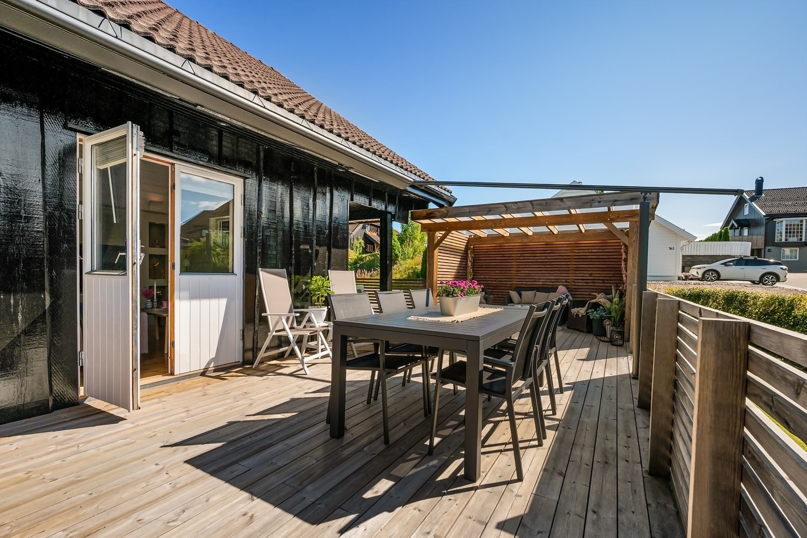 Stor og solrik terrasse med tilgang fra stue, gårdsplass og via trapp fra gressplen Galleribilde