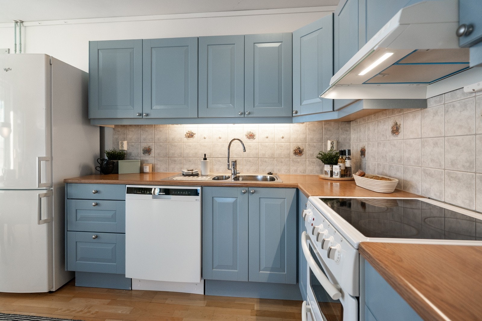 Kjøkkeninnredning med profilerte fronter, laminert benkeplate og fliser over benken. Galleribilde