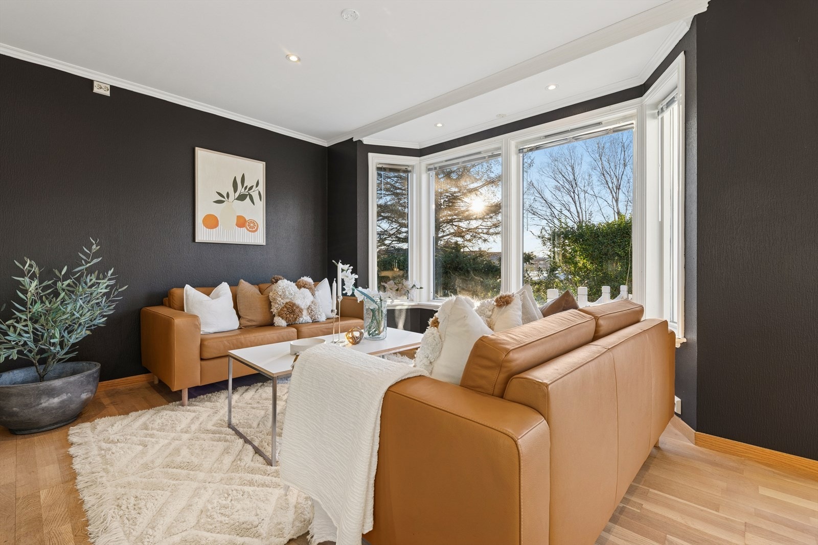 Stuen har parkett på gulvet, svartmalte vegger og hvitt tak med spotter. Galleribilde