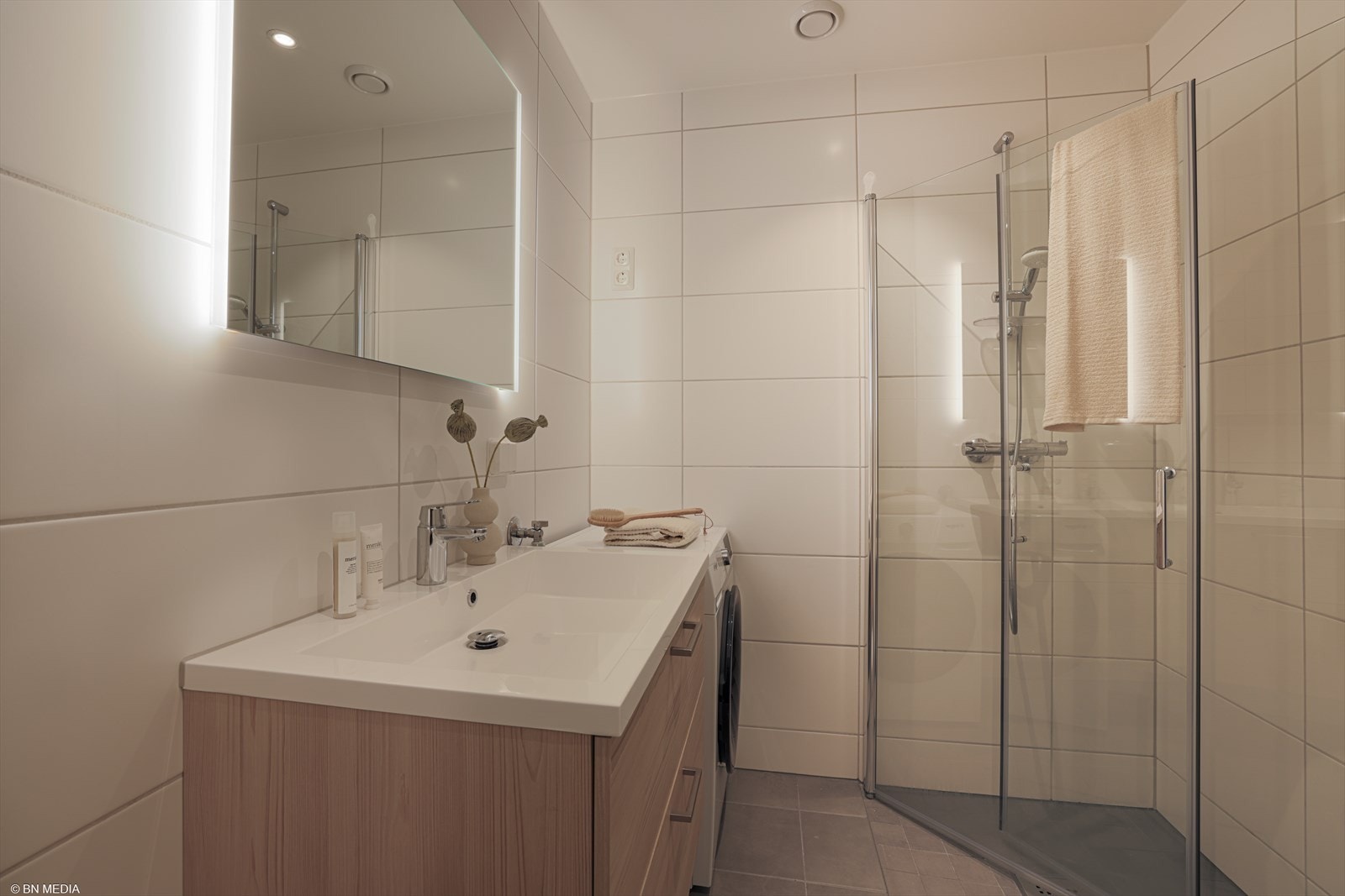 Badet er utstyrt med dusjhjørne med innfellbare glassdører med vegghengt dusjsett, veggmontert toalett og opplegg for vaskemaskin. Galleribilde