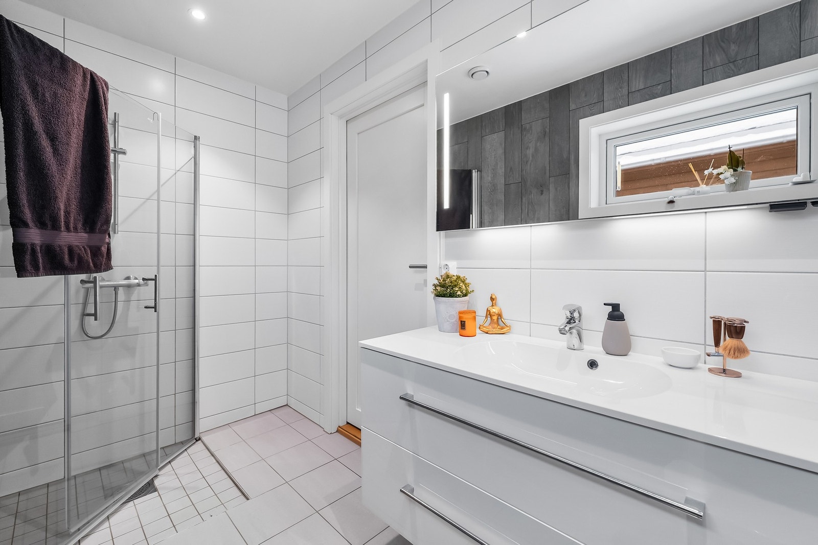 Smakfullt hovedbad med delikate fliser på gulv- og veggflater, samt varmekabler i gulv Galleribilde