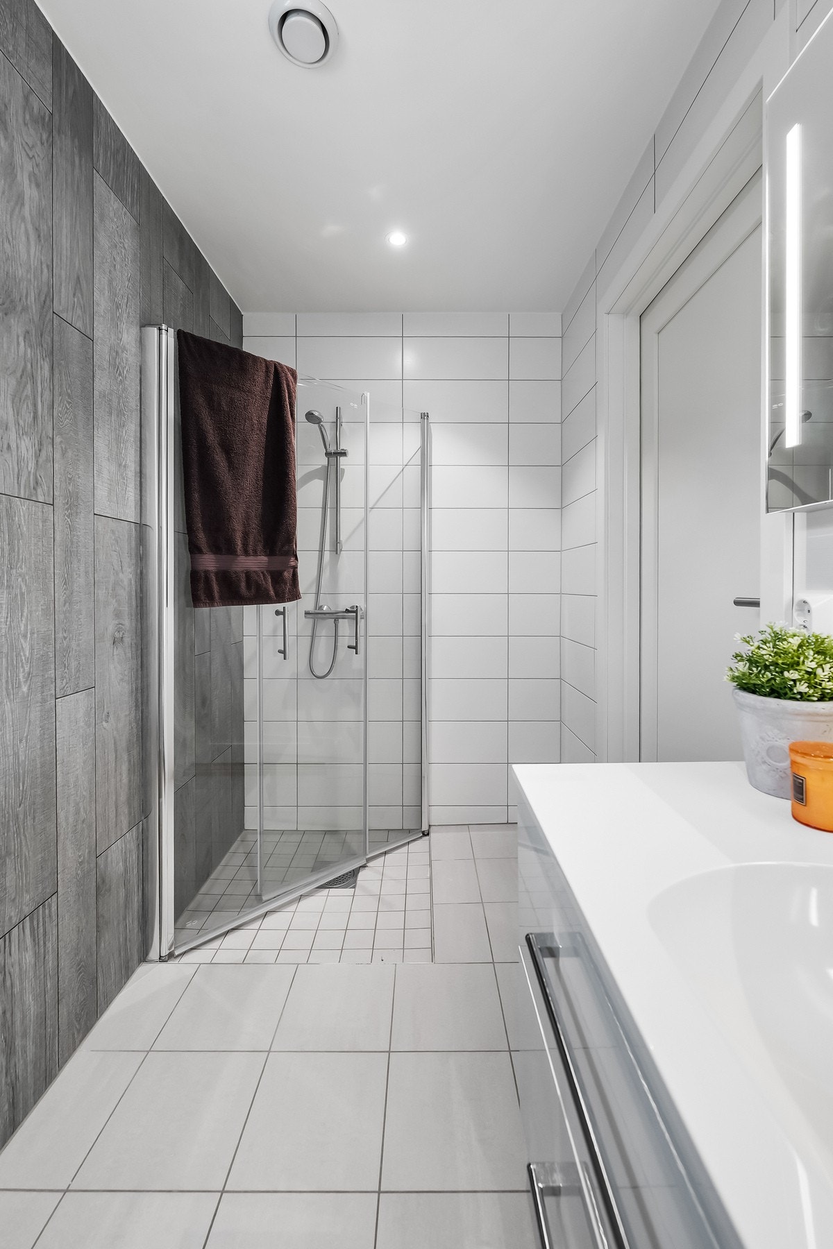 Videre har badet et separat dusjhjørne med hånddusj og innfellbare dusjdører i glass. Galleribilde