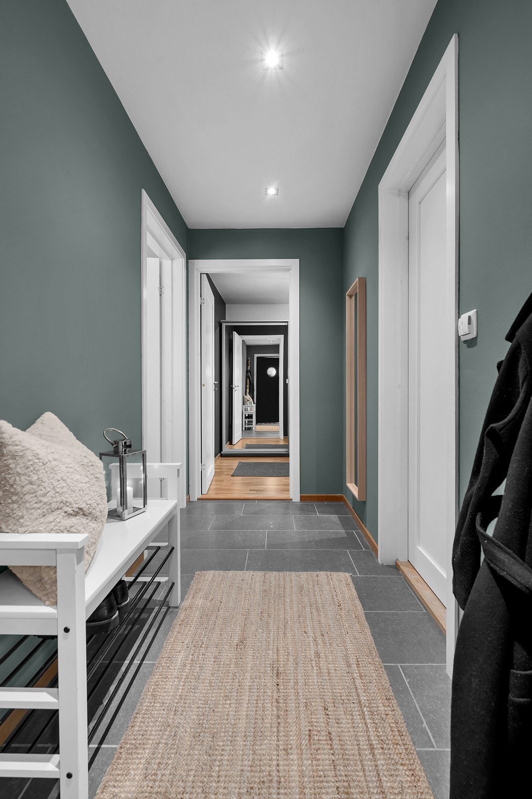 Innbydende og flislagt entrè med varmekabler i gulv. Til høyre finner man et praktisk vaskerom, men vi starter først i stuen. Galleribilde