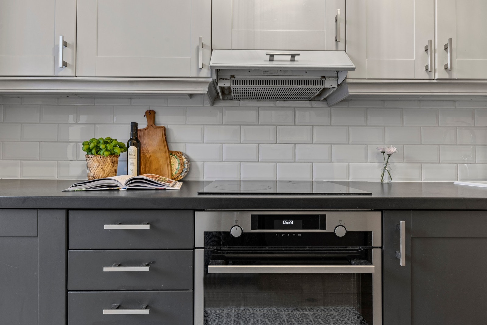 Kjøkkeninnredning med malte fronter, overskap med benkebelysning og fliser på vegg Galleribilde