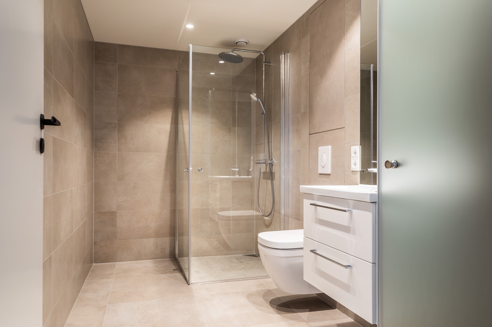 Delikat flislag bad med moderne innredning. Opplegg for vask/tørk bak "frostet" dør Galleribilde