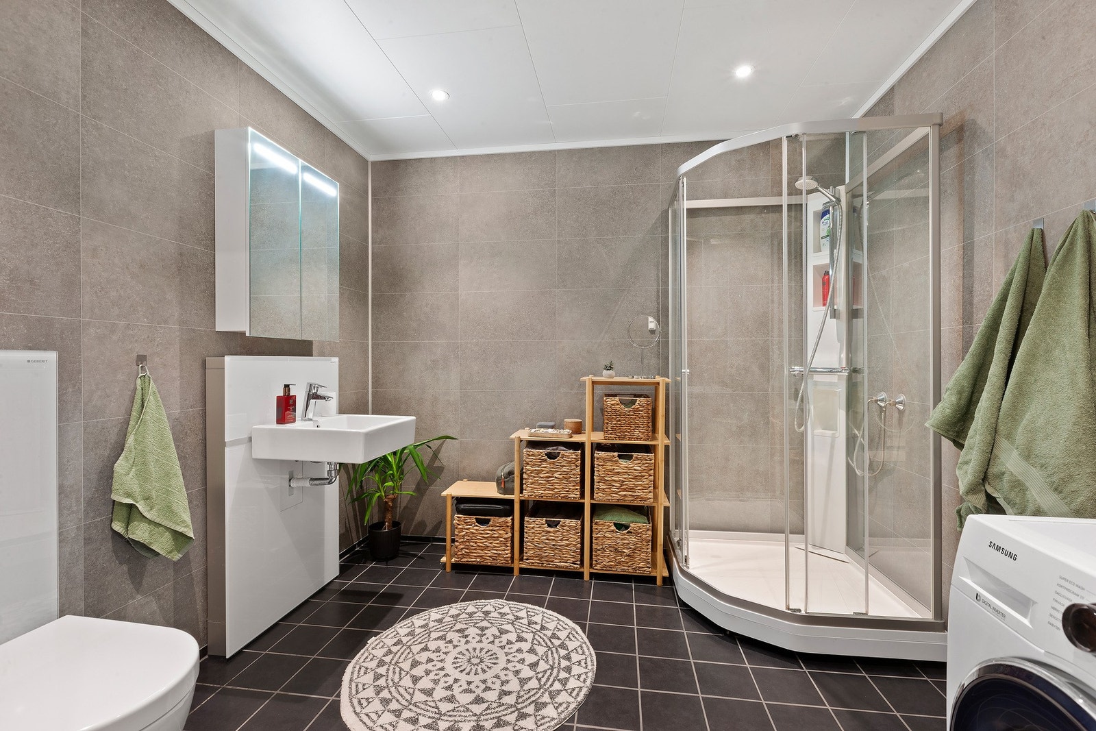 Bad/vaskerom i moderne overflater, vegghengt toalett og god boltreplass. Galleribilde