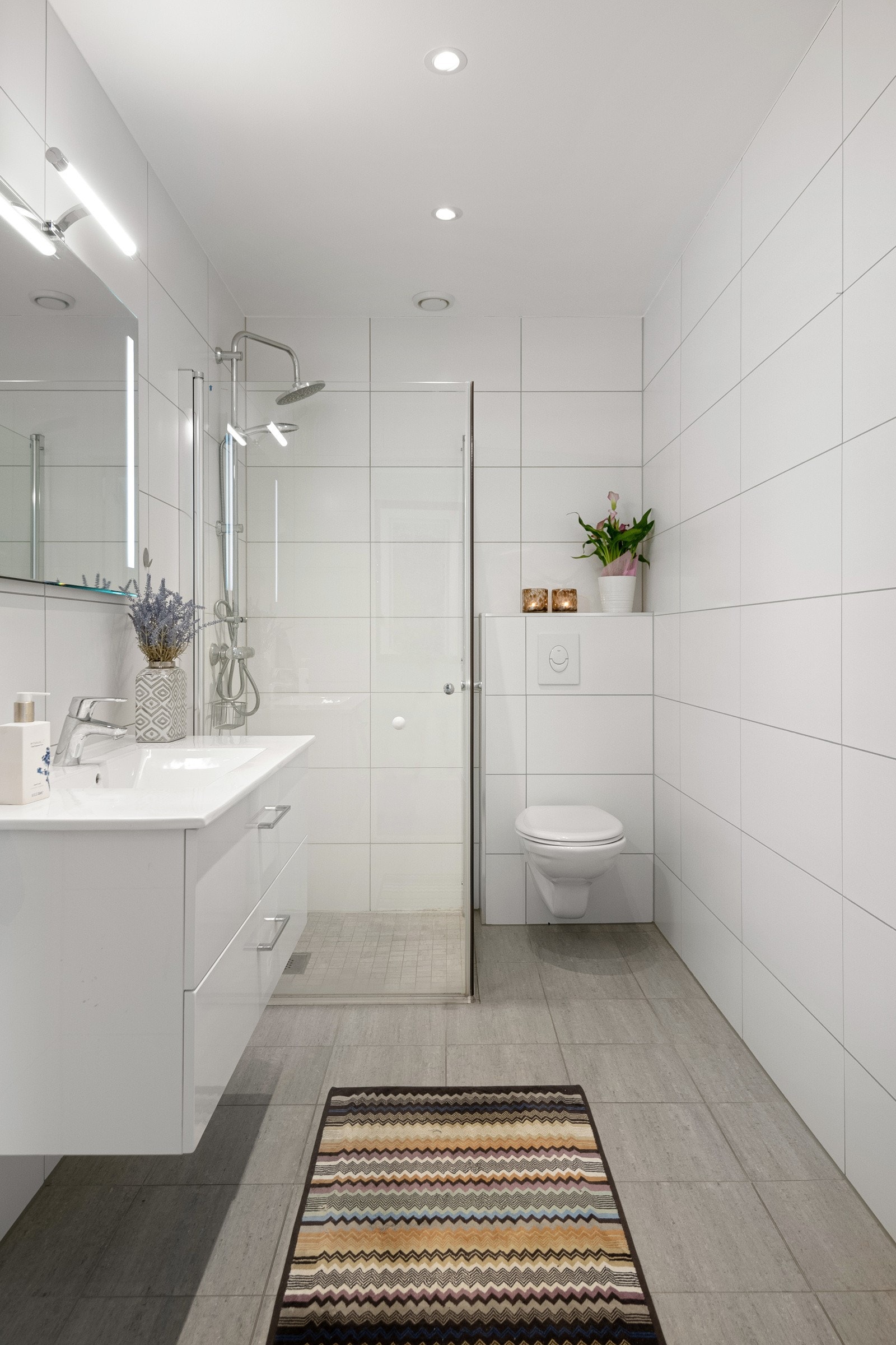 Himlingen er malt og utstyrt med stilige spotlights som lyser opp rommet. Praktisk innredning med servant, toalett, dusjinnredning med glatte overflater og et speil med lys. Galleribilde