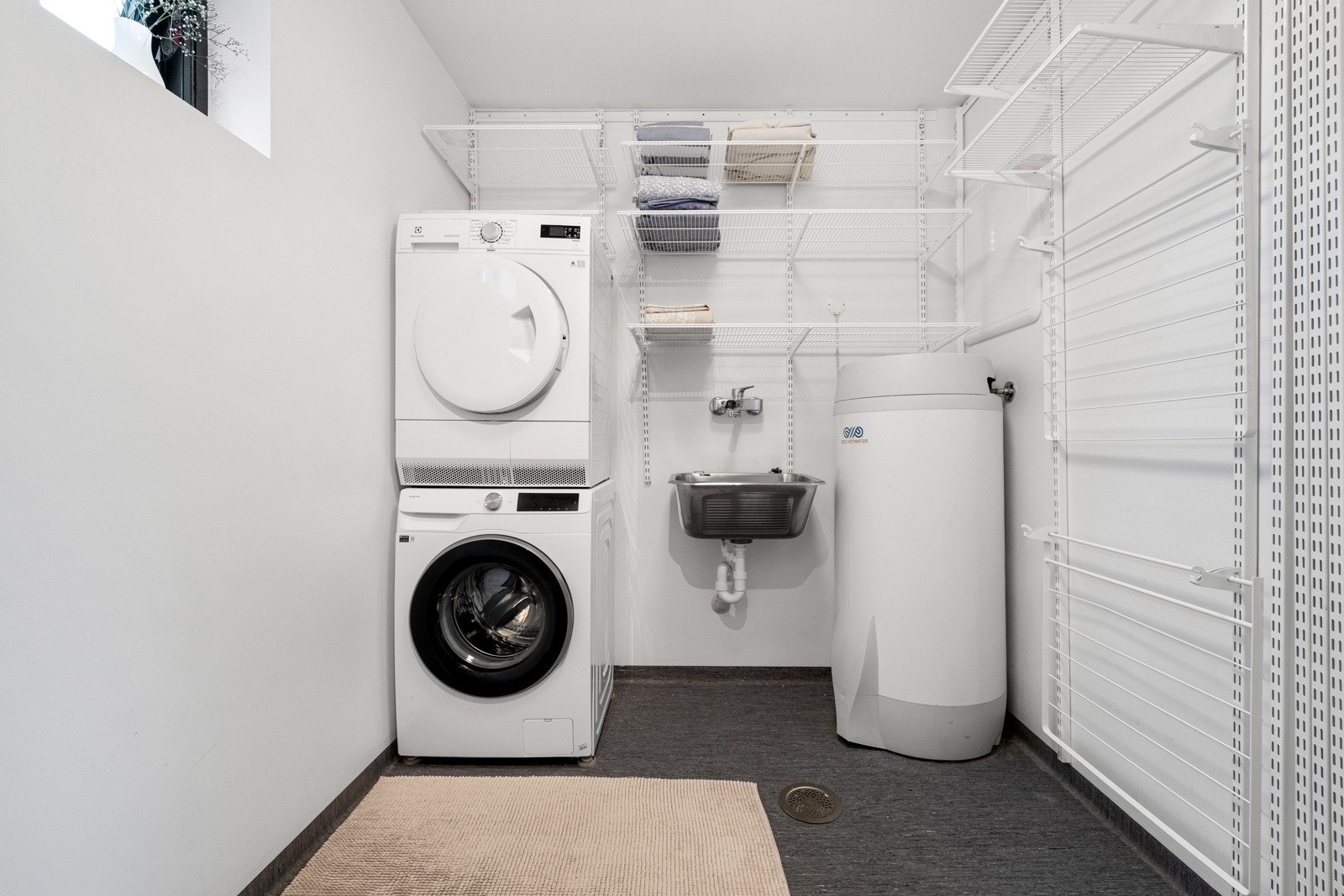 Vaskerommet er praktisk innredet med opplegg for vaskemaskin og tørketrommel, her er utslagsvask og varmtvannstank. Her kan man enkelt sette opp en skyvedør eller lignende om man ønsker å ha dette som et separat rom. Galleribilde