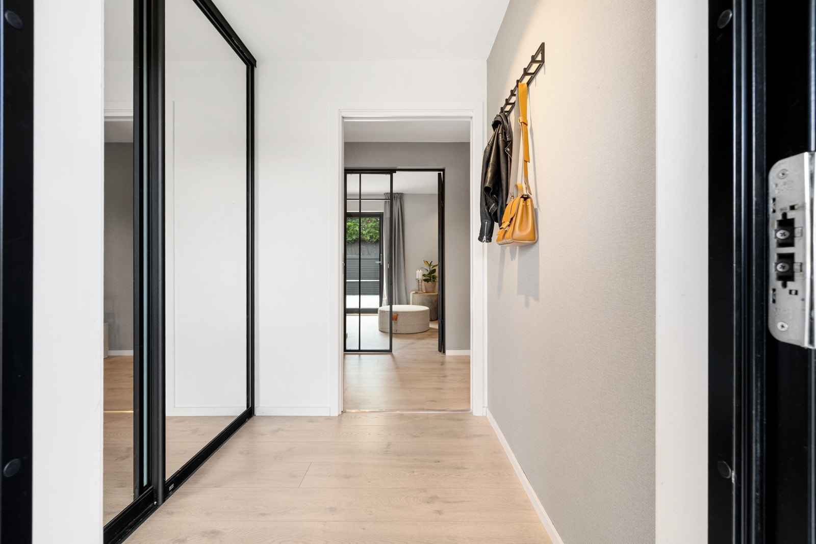 I entréen er det en romslig skyvedørsgarderobe med speildører og sorte profiler fra LEBA. Galleribilde
