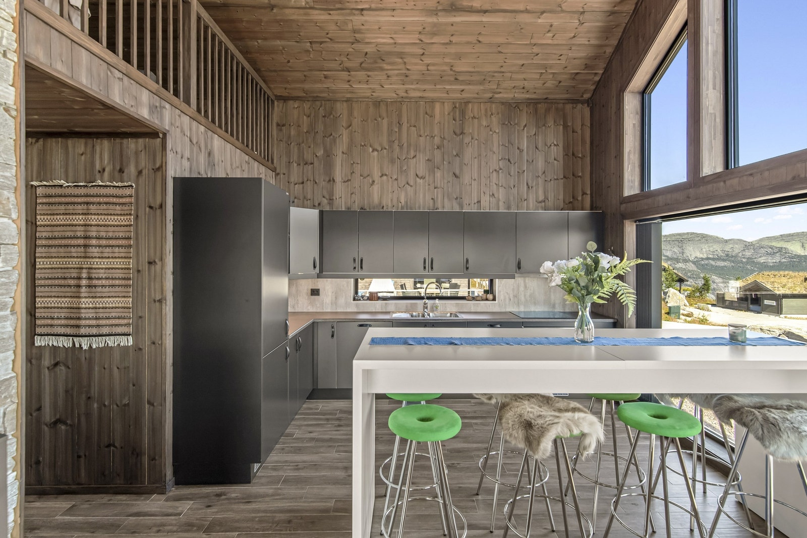 Kjøkkenet er et stilrent Huseby-kjøkken med åpen løsning mot stuen. Her er det flislagt gulv med gulvvarme, beiset trepanel på vegger og himling, slette fronter, laminert benkeplate og nedfelt oppvaskkum i metall. Galleribilde