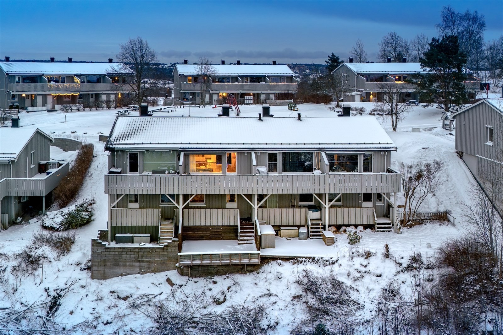 Boligen ligger i skrånende terreng, og begge de to soverommene her nede har vinduer ut på terrassen. Det ene har en balkongdør. Trappen leder ned til et lavere nivå som liksom svever over skogen. Galleribilde