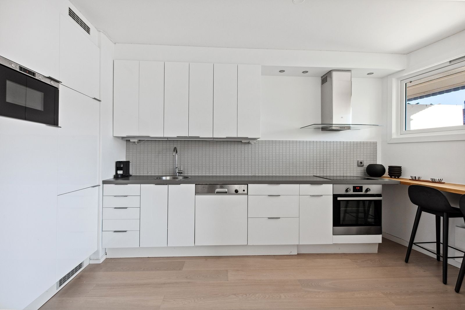 Kjøkken med integrerte hvitevarer, god benk- og skapplass, samt barløsning under vinduet Galleribilde