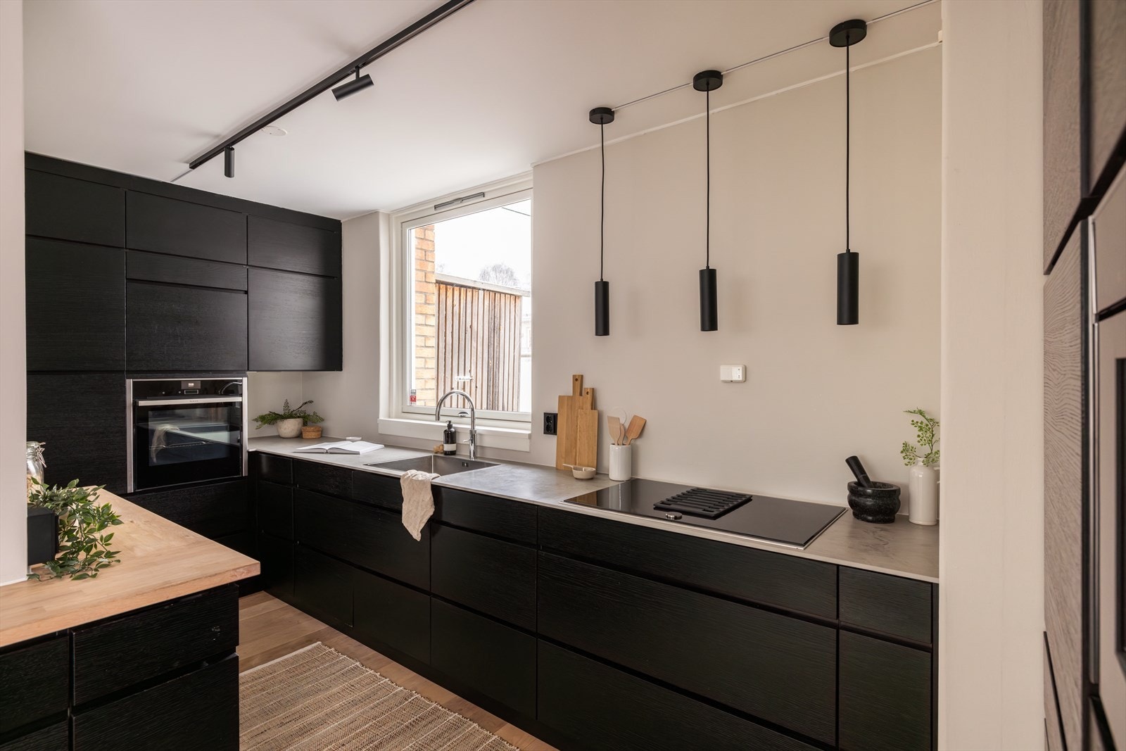 Kvik kjøkkeninnredning med glatte fronter. Stekeovn, platetopp, kaffemaskin, vinskap, oppvaskmaskin og kjøleskap er integrert i innredningen. Galleribilde