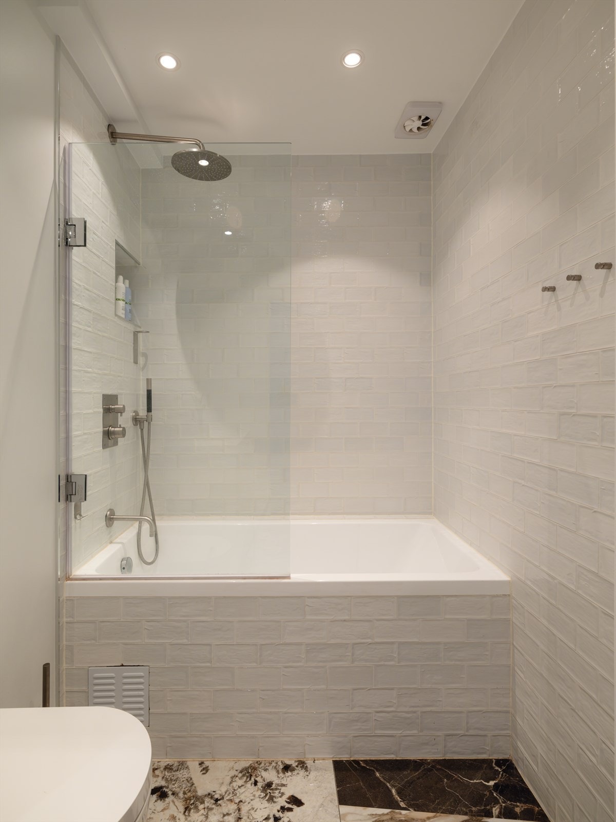 Innredning bestående av benkeskap og veggskap med speil og glatte fronter, dusj i badekar, veggfestet klosett med innebygget sisterne og opplegg for vaskemaskin Galleribilde