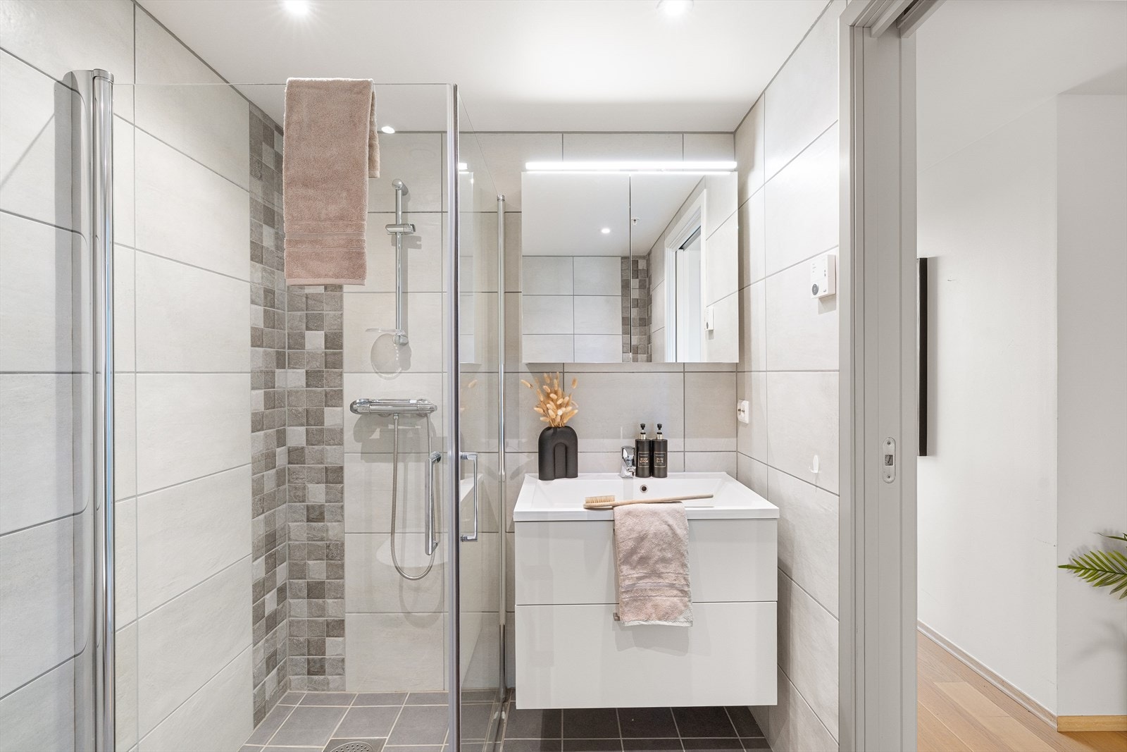 Badet er utstyrt med dusjhjørne, servant og vegghengttoalett. Galleribilde