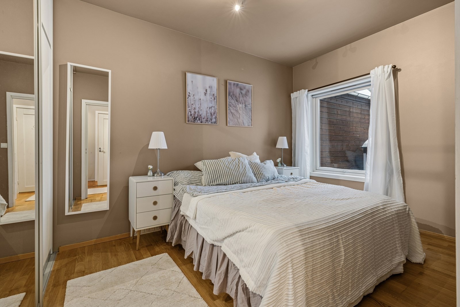 Soverommet i første etasje er romslig og innredningsvennlig, med god plass til både dobbelseng og nattbord. Det store vinduet slipper inn rikelig med naturlig lys og bidrar til en lys og behagelig atmosfære i rommet. Galleribilde