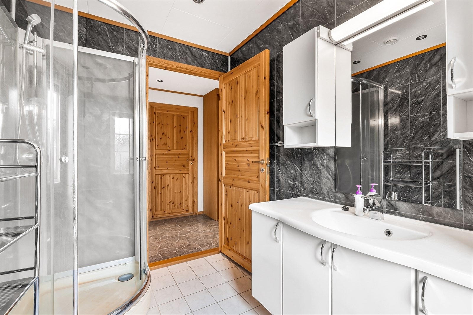 Bad er innredet med nedfelt servant, veggmontert toalett og dusjkabinett Galleribilde