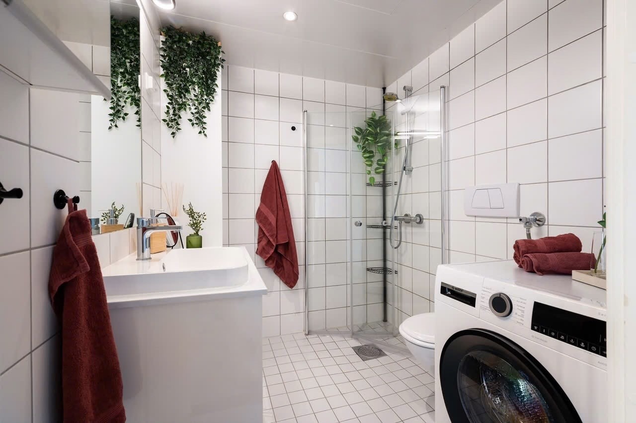 Pent flislagt bad med hjørnedusj, servant, toalett og opplegg for vaskemaskin Galleribilde