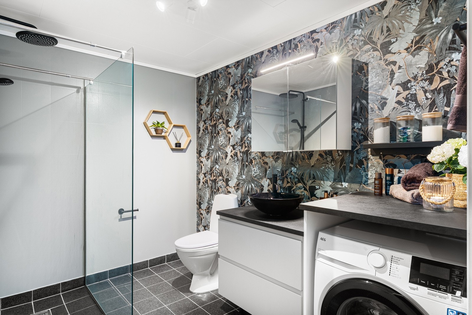 Moderne innredet med toalett, dusjhjørne, benkeplate og opplegg til vaskemaskin Galleribilde