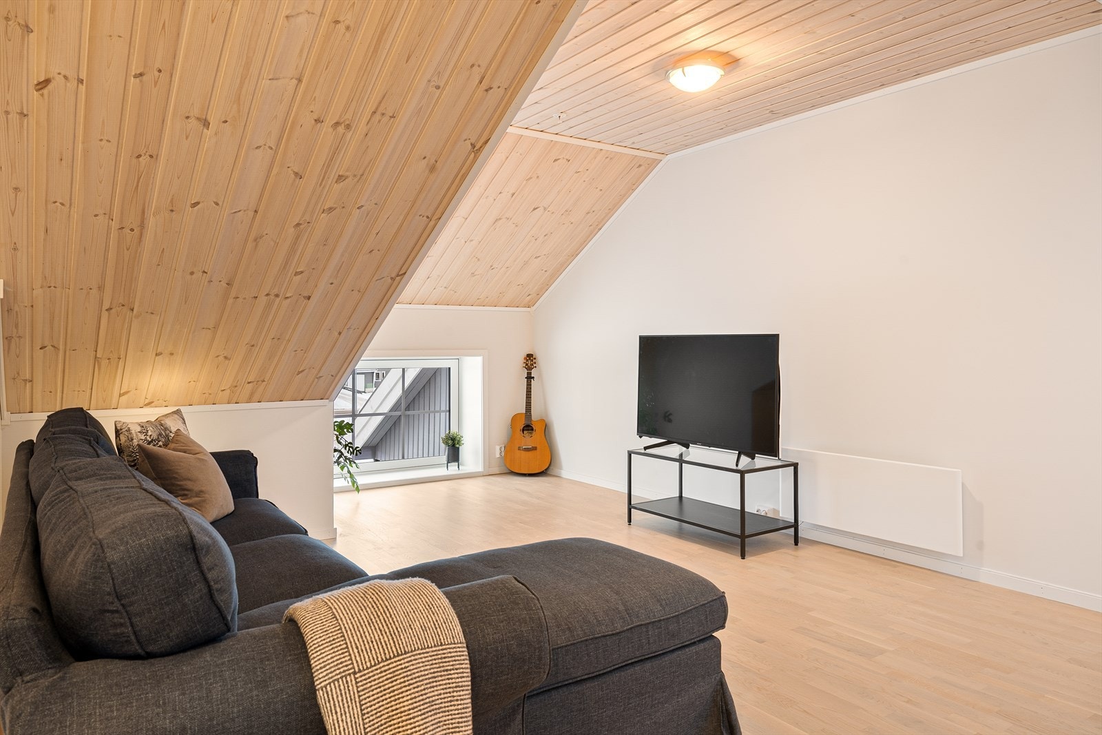 Hyggelig loftstue med skråtak med furupanel Galleribilde