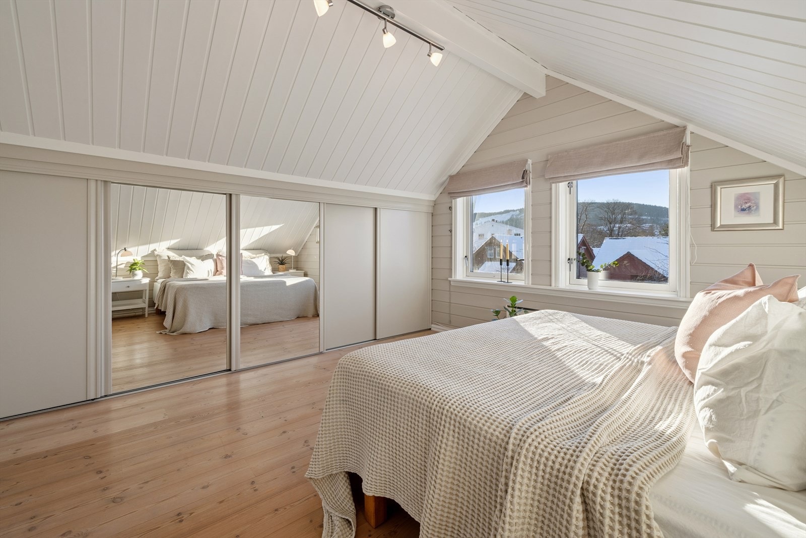 Det ene soverommet er utstyrt med en praktisk skyvedørsgarderobe integrert i skråveggen, som gir smart og effektiv oppbevaring uten å oppta unødig gulvplass. Galleribilde