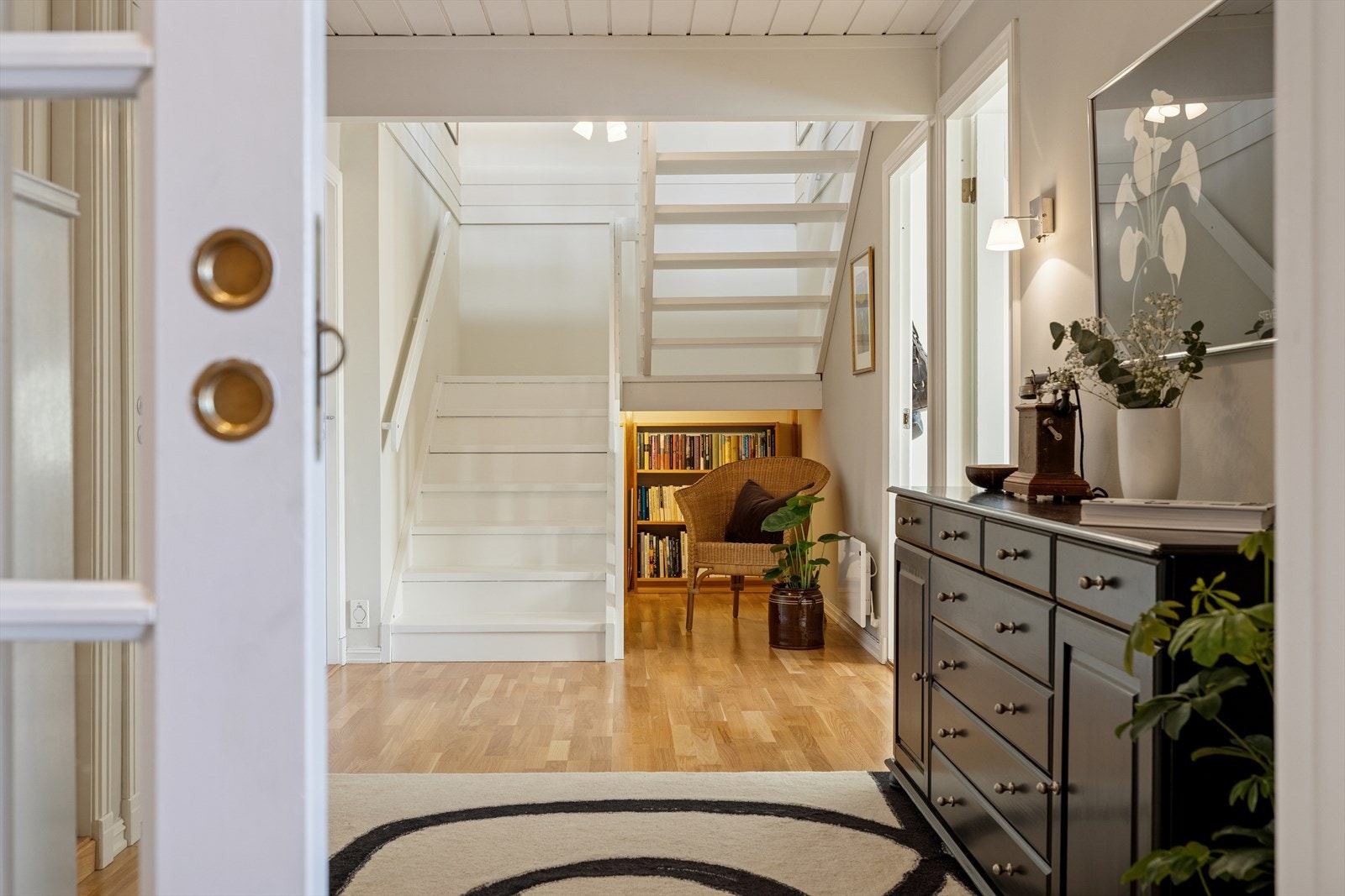 Fra mellomgangen leder en trapp opp til en romslig stue, spisestue og kjøkken i en åpen og innbydende løsning. Galleribilde