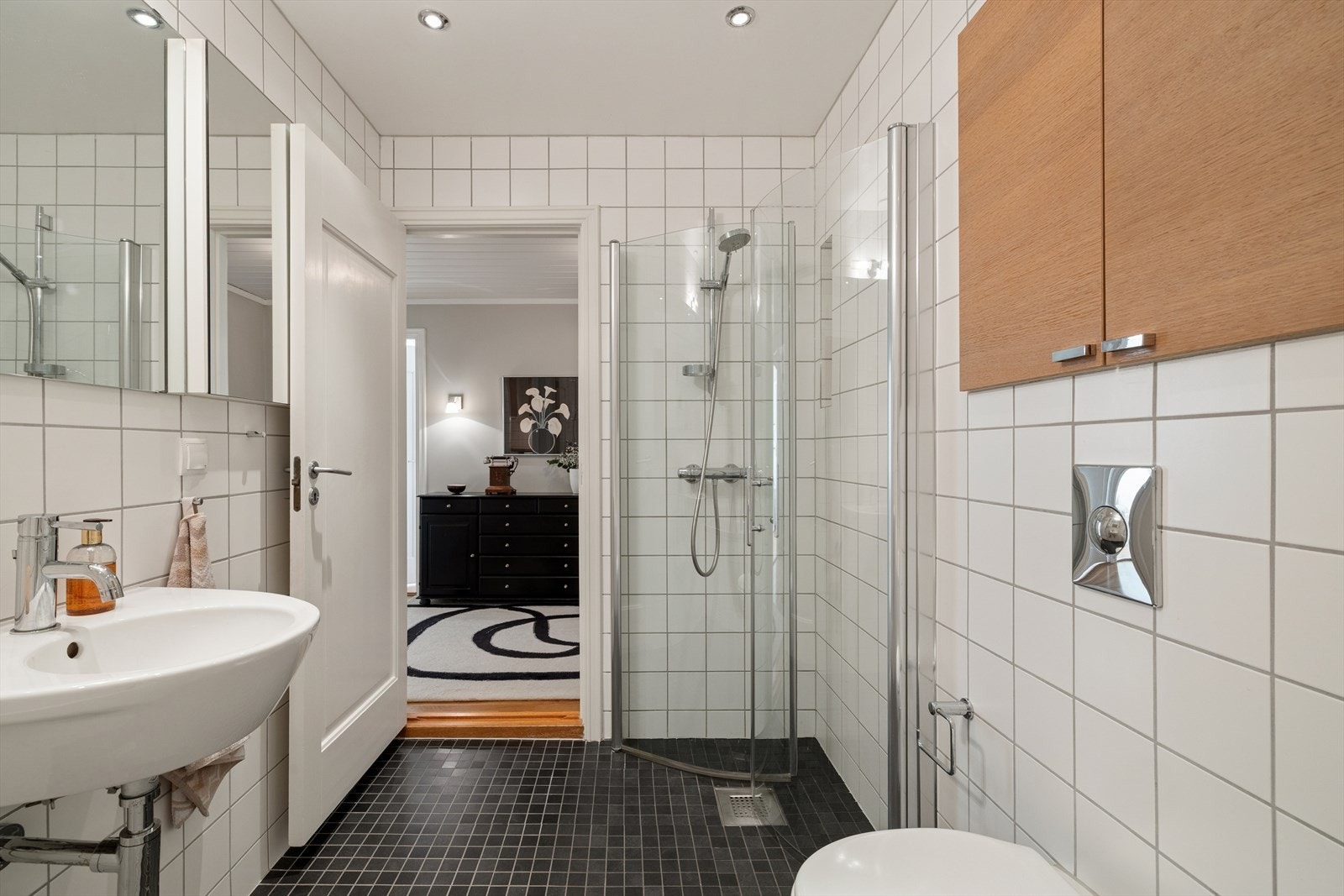 Baderommet fremstår som funksjonelt og tidsriktig, med fliser på både gulv og vegger. Himlingen er malt og utstyrt med innfelte downlights som sørger for en jevn og behagelig belysning. Elektriske varmekabler i gulv for varme og velvære. Galleribilde