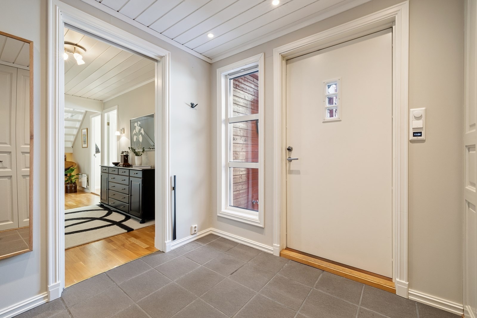 Man ønskes velkommen inn i en lys og romslig entré som gir et meget godt førsteinntrykk. Fliser på gulvet gjør rommet både praktisk og stilrent, og et sidevindu ved inngangsdøren slipper inn rikelig med dagslys som skaper en inviterende atmosfære. Galleribilde