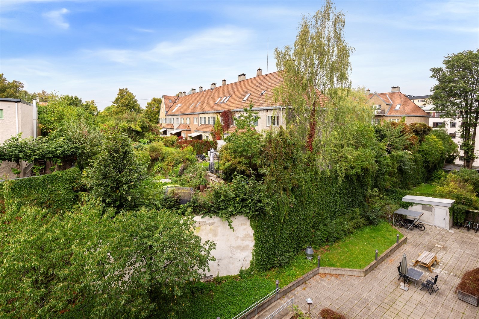 Stue med fransk balkong og idyllisk utsyn over nabolaget og fellesarealer. Bilde tatt i sommer for å vise den grønne utsikten. Galleribilde