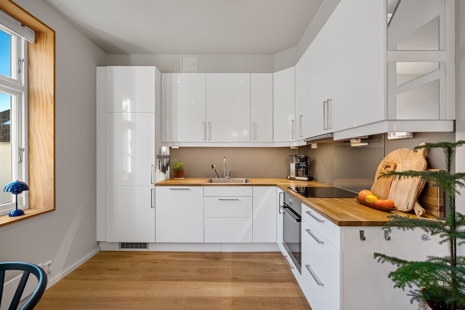 Praktisk L-formet kjøkken med glatte, lyse fronter. Galleribilde