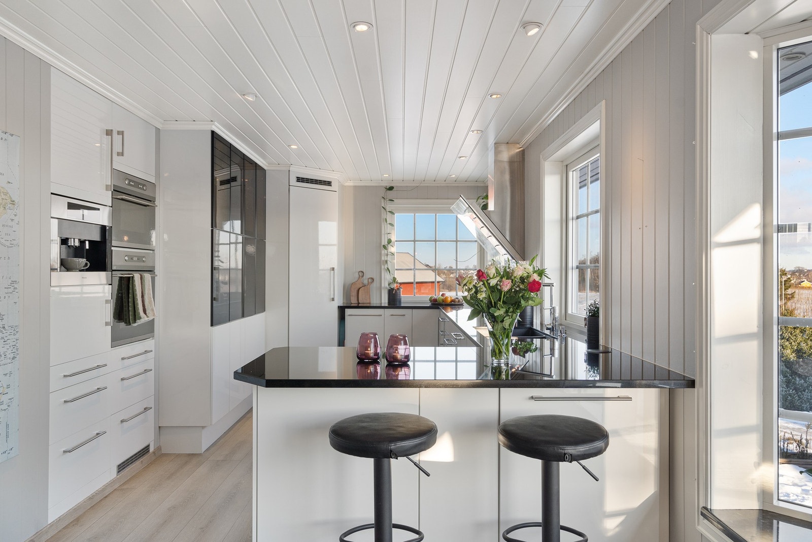 Lekkert kjøkken med innredning og hvitevarer samt steinplater for enkel og praktisk bruk Galleribilde