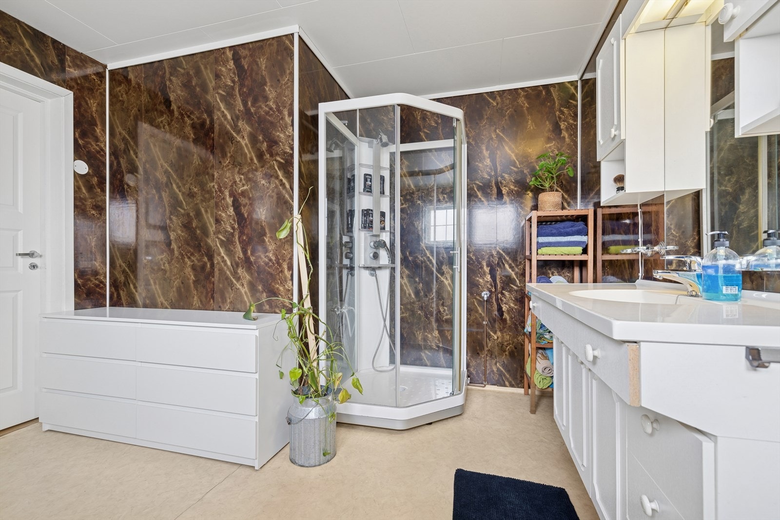 Innredningen består av speil, servant med oppbevaringsseksjon, dusjkabinett og gulvmontert toalett. Galleribilde