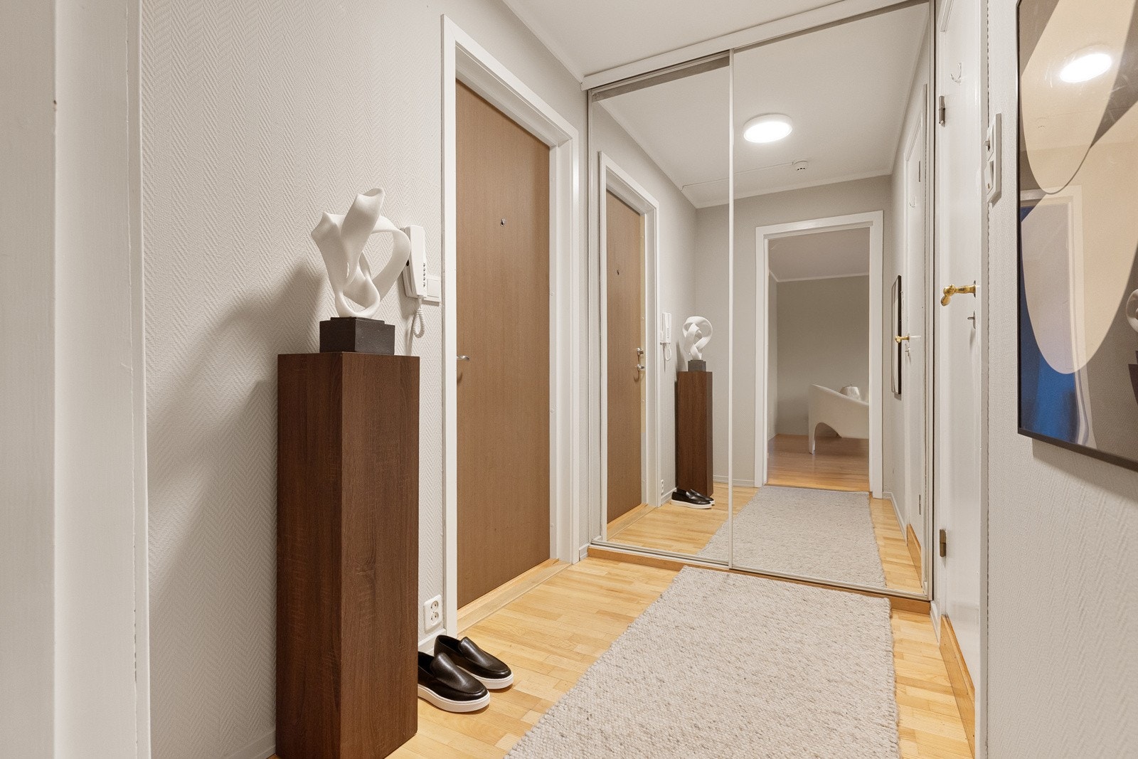 Entréen er lys med plass til kommode eller sittebenk. Det er innredet med en stor skyvedørsgarderobel, hvor yttertøy kan ryddes bort Galleribilde