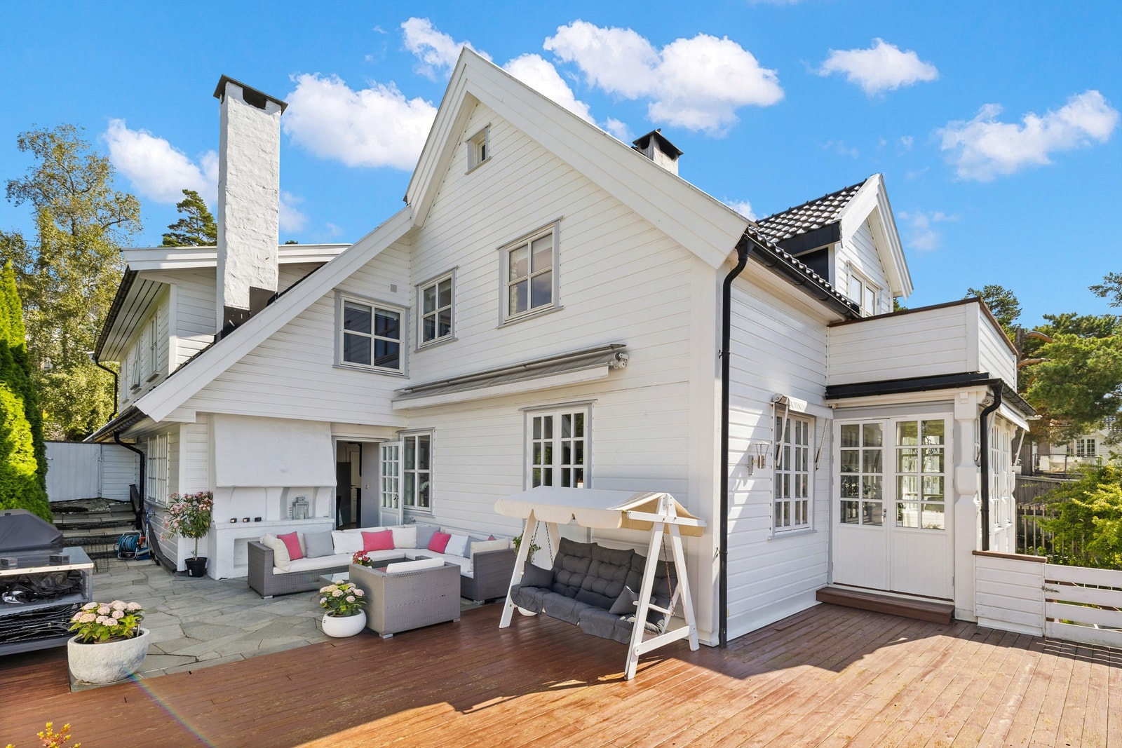 Stor og solrik terrasse med utepeis og trapp til hagen Galleribilde