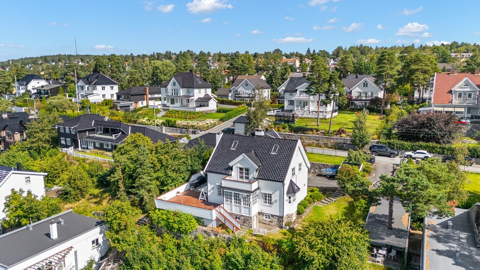 Stor og solrik tomt med utsikt som er pent opparbeidet med plenarealer, prydbusker og diverse beplantning. Asfaltert innkjøring og gårdsplass. Noe naturtomt i skråningen mot vest nedenfor terrassen Galleribilde