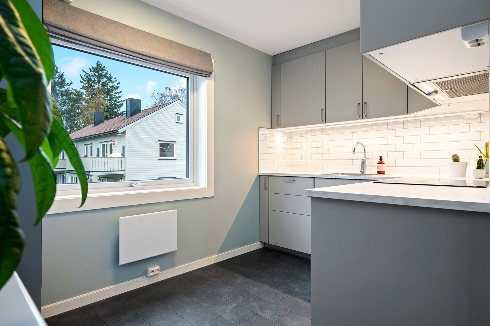 Moderne kjøkken med glatte fronter og laminat benkeplate. Stor vindusflate gir godt lysinnslipp og en trivelig arbeidsplass. Galleribilde