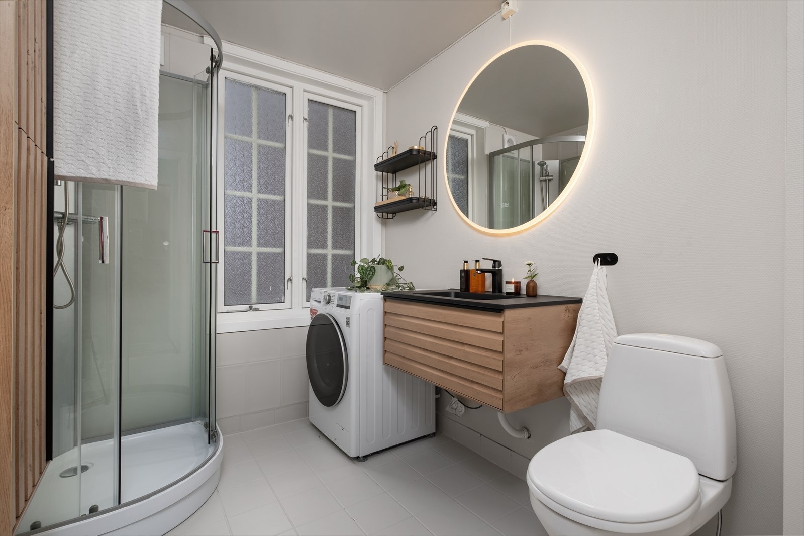 Pent bad med moderne servant med underskap og opplegg for vaskemaskin. Galleribilde